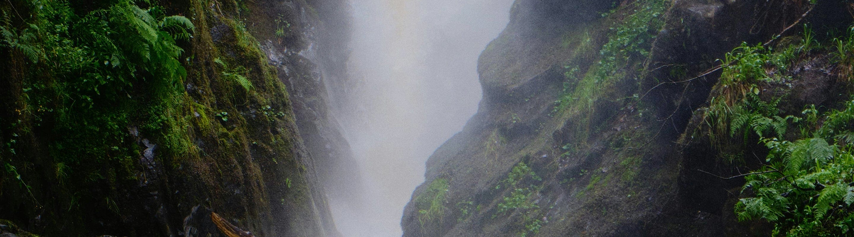 A natural landscape of a waterfall between two rock faces of a mountain with plants