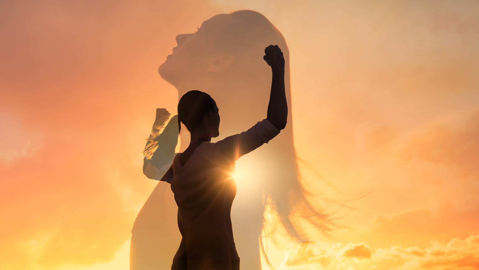 Shadow of a woman with her arms in the air showing her strength with a sunset background
